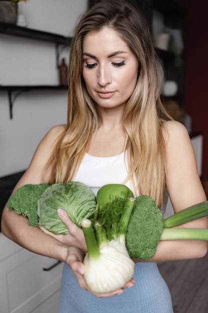 Kobieta fitness trzyma pełne świeżych surowych zielonych warzyw