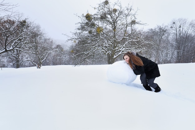 Kobieta formuje ze śniegu dużego bałwana