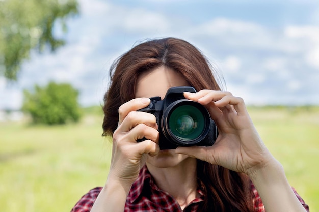 Kobieta fotograf fotografuje aparatem na niewyraźnym tle