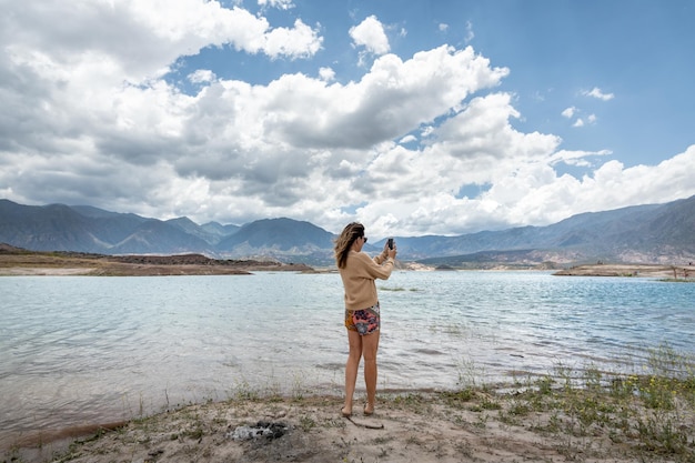 kobieta fotografująca krajobraz laguny potrerillos telefonem komórkowym w mendozie w argentynie