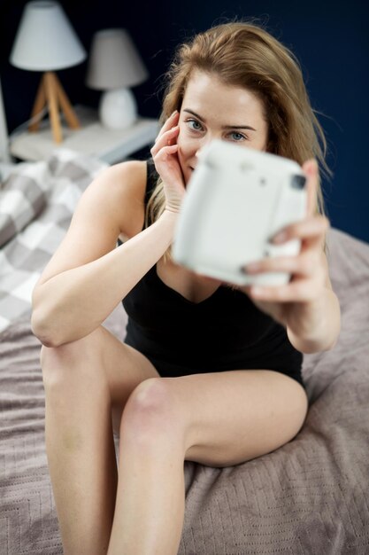 Zdjęcie kobieta fotografująca siedząc na łóżku