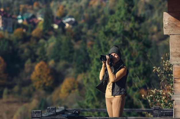 Kobieta fotografuje jesienny krajobraz górski aparatem DSLR.