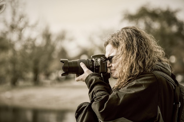 Kobieta fotografuje przez kamerę przeciwko drzewom