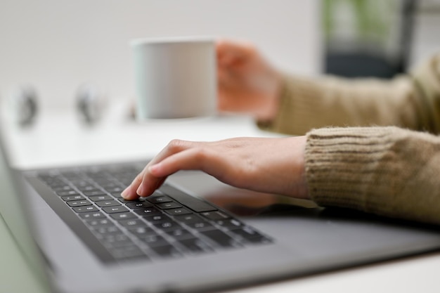 Kobieta freelancer pracująca przy biurku przy użyciu komputera przenośnego, popijając kawę