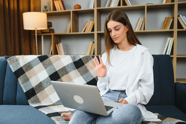Kobieta freelancer pracująca z laptopem w domu na kanapie Portret pracującej dziewczyny