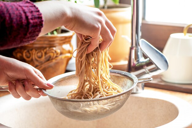 Zdjęcie kobieta gotuje makaron soba w kuchni.