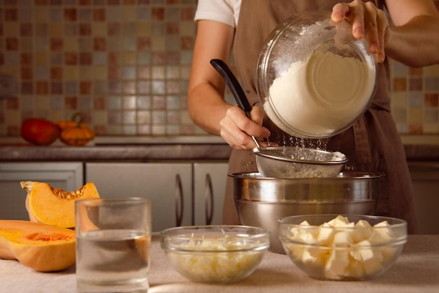 Zdjęcie kobieta gotuje wegański placek z dyni na wiejskim brązowym stole kuchennym z składnikami