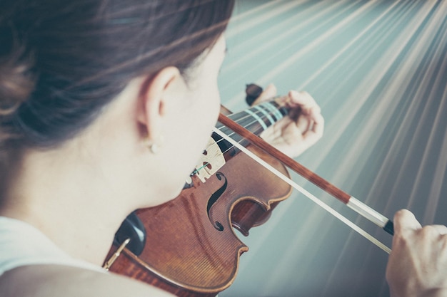 kobieta gra na skrzypcach w muzyce, jak muzyk lub skrzypaczka pokazuje struny w portrecie ze słońcem