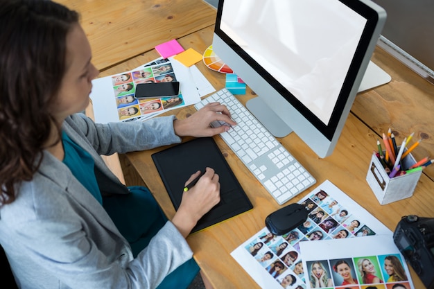 Kobieta grafik za pomocą tabletu graficznego przy biurku