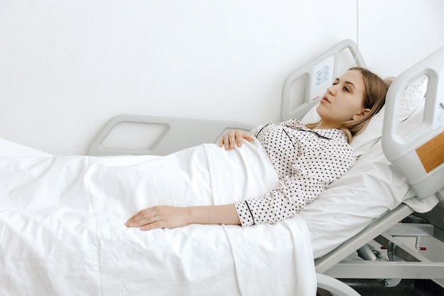 Kobieta hospitalizowana Młoda kobieta leżąca w szpitalnym łóżku koncepcja medycyny i opieki zdrowotnej