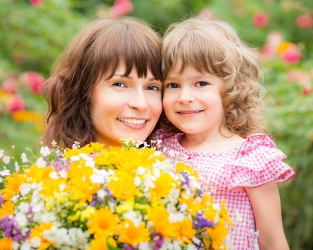 Kobieta i dziecko z bukietem kwiatów na zielonym tle Koncepcja wiosennych wakacji rodzinnych Dzień matki