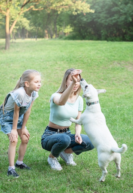 Kobieta i dziewczynka bawią się z psem rasy Jack Russell Terrier