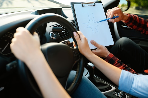 Zdjęcie kobieta i instruktor z listą kontrolną w samochodzie, szkoła jazdy. człowiek uczy pani prowadzić pojazd. edukacja na prawo jazdy