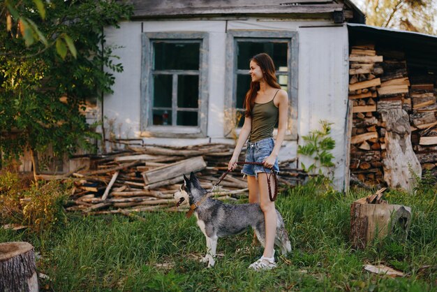 Zdjęcie kobieta i jej pies husky szczęśliwie bawią się na świeżym powietrzu w parku wśród drzew uśmiechają się z zębami jesienią spacery z jej zwierzęciem zdjęcie wysokiej jakości