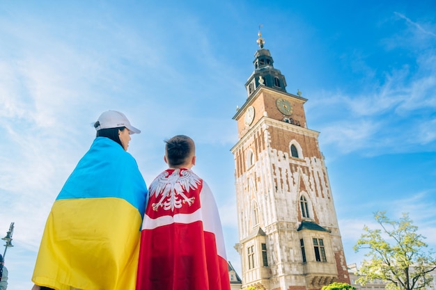 Kobieta i mały chłopiec pokryci flagą Ukrainy i Polski w centrum miasta