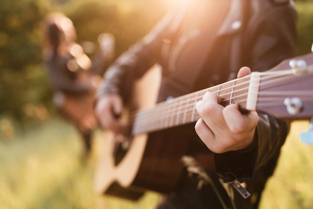 Kobieta i mężczyzna grający na gitarze akustycznej w przyrodzie o zachodzie słońca