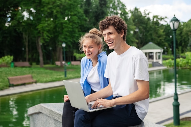 Kobieta i mężczyzna w miejskim parku w stylu casual, wykorzystując technologię do wspólnej pracy na świeżym powietrzu na laptopie