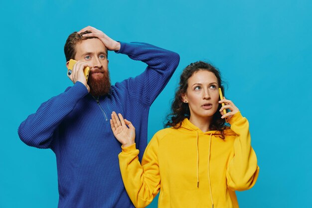 Zdjęcie kobieta i mężczyzna wesoła para z telefonami w rękach krzywy uśmiech wesoły na niebieskim tle koncepcja prawdziwych relacji rodzinnych rozmawiających przez telefon działa online