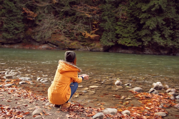 Kobieta idąca w pobliżu rzeki upadłe liście natura góry wysokiej jakości zdjęcie