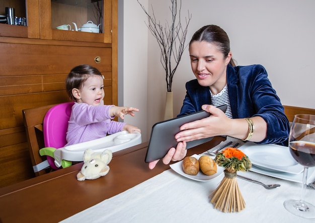 Kobieta interesu matka i szczęśliwa dziewczynka patrząc na komputer typu tablet siedzący przy stole w restauracji