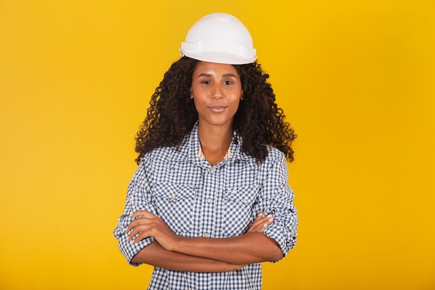 Kobieta inżynier lub architekt na żółtym tle uśmiechając się z rękami skrzyżowanymi.