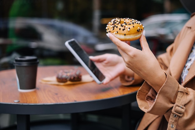 Kobieta je pączki i patrzy na telefon