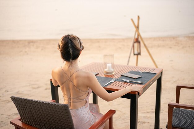Kobieta jedząca prywatną kolację na tropikalnej plaży podczas romantycznego zachodu słońca