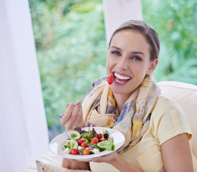 Zdjęcie kobieta jedząca sałatkę i jedzenie dla odżywiania warzyw i obiad z szczęściem na portrecie dieta wellness i zdrowy posiłek wegański dla cholesterolu z uśmiechem detoks i przekąską na obiad w domu
