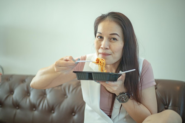 Kobieta jedząca spaghetti na brązowej skórzanej kanapie