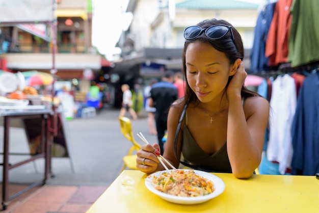 Kobieta jedzenie makaronu Pad Thai przy drodze Khao San