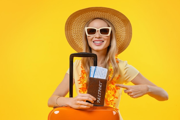 Kobieta jedzie na wakacje z walizką i paszportem wskazując na pojedyncze żółte tło