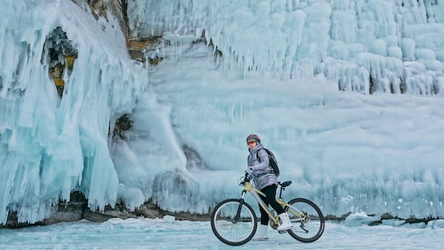 Kobieta jedzie rowerem po lodzie Dziewczyna ubrana jest w srebrzysty plecak z puchową kurtką