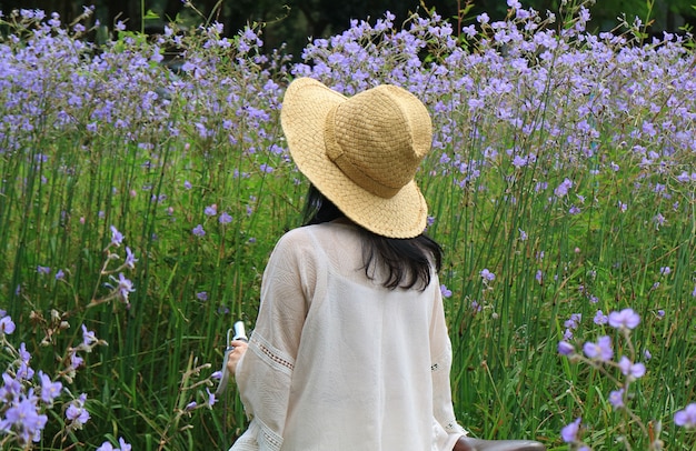Kobieta jest ubranym słomianego kapelusz z jej rowerowym patrzeje pięknym pastelowym purpurowym kwiatu polem