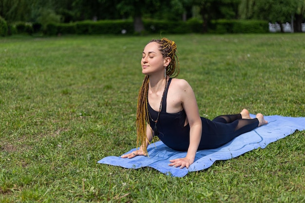 Kobieta jogin z dredami ćwicząca pozycję psa skierowanego w górę urdhva mukha svanasana na macie do jogi