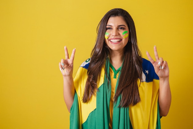 Kobieta kibica mistrzostw świata w piłce nożnej w Brazylii 2022 używając flagi brazylijskiej jako okładki Pokój i miłość