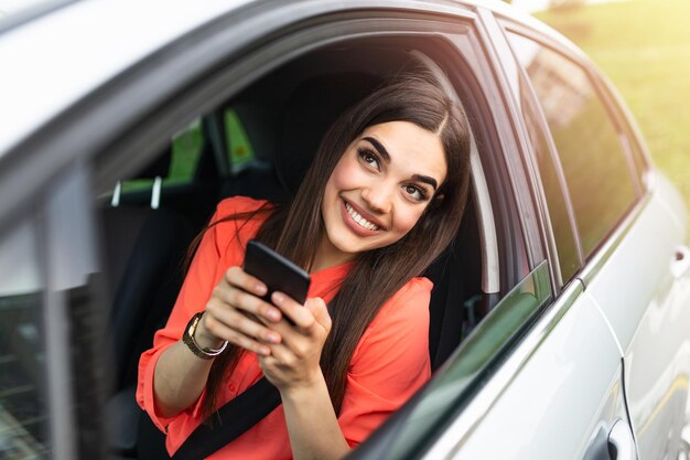 Kobieta kierowca używająca smartfonu w samochodzie Kobieta kierowcy używająca smartfona w samochodzie Wycieczka rekreacyjna technologia podróży i ludzie koncepcja Szczęśliwa kobieta kierująca samochodem ze smartfonem