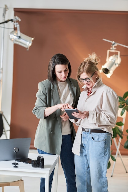 Kobieta korzysta z cyfrowego tabletu razem ze swoim kolegą, gdy stoją w biurze