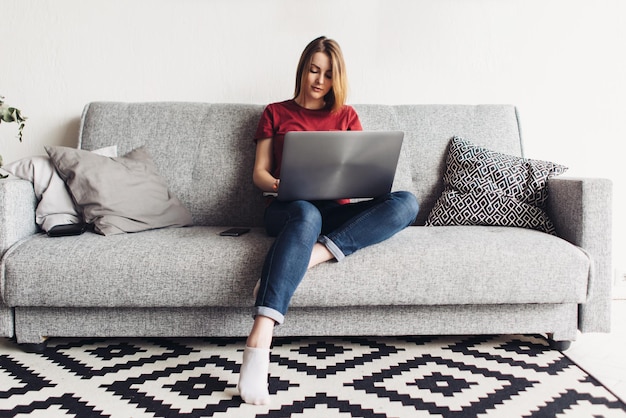 Kobieta korzysta z laptopa siedząc na kanapie w salonie