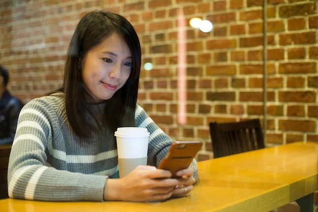 Kobieta korzysta z telefonu komórkowego w kawiarni