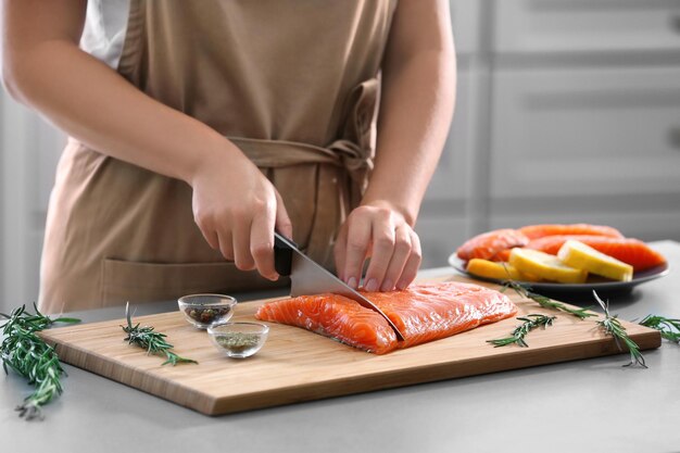 Zdjęcie kobieta kroi świeży filet z łososia w kuchni