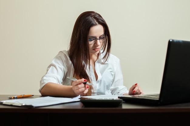 Kobieta księgowa w okularach za pomocą laptopa