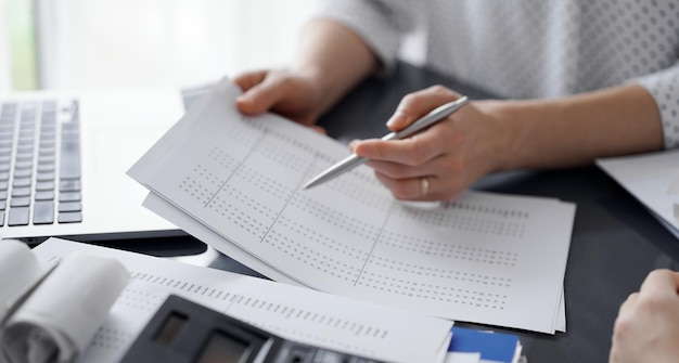 Kobieta-księgowa wskazująca długopisem na dokument kontrolny, wyjaśniając wyniki liczenia podatków, z bliska. Koncepcje audytu biznesowego i finansów.