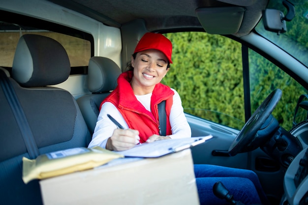 Kobieta kurier w furgonetce sprawdzania dokumentów przed dostarczeniem przesyłki.