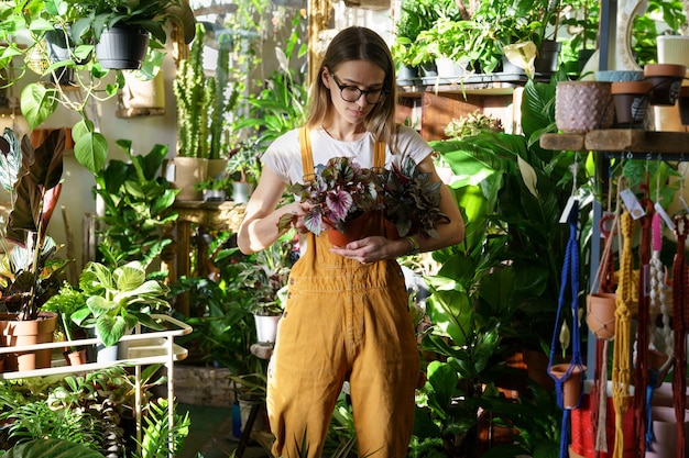 Kobieta kwiaciarnia pracuje w szklarni młody ogrodnik trzyma doniczkową roślinę doniczkową na sprzedaż w kwiaciarni