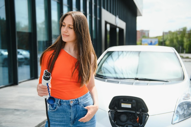 Kobieta ładująca samochód elektryczny na stacji benzynowej