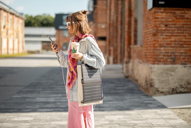 Kobieta ładuje Telefon Z Przenośnego Panelu Słonecznego Podczas Spaceru Na świeżym Powietrzu