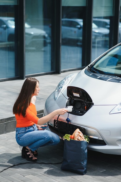 Kobieta ładuje wypożyczony samochód elektryczny