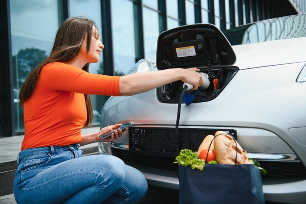 Kobieta ładuje wypożyczony samochód elektryczny