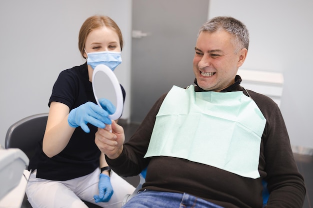 Kobieta lekarz dentysta pokazujący wynik leczenia zębów