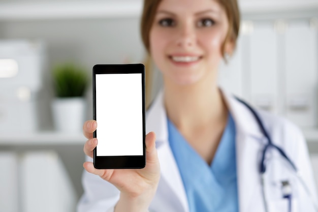 Kobieta lekarz medycyny trzymając telefon komórkowy i pokazując go. Sprzęt medyczny, nowoczesna technologia i koncepcja komunikacji